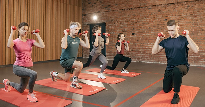 Group of people taking a gym class with weights