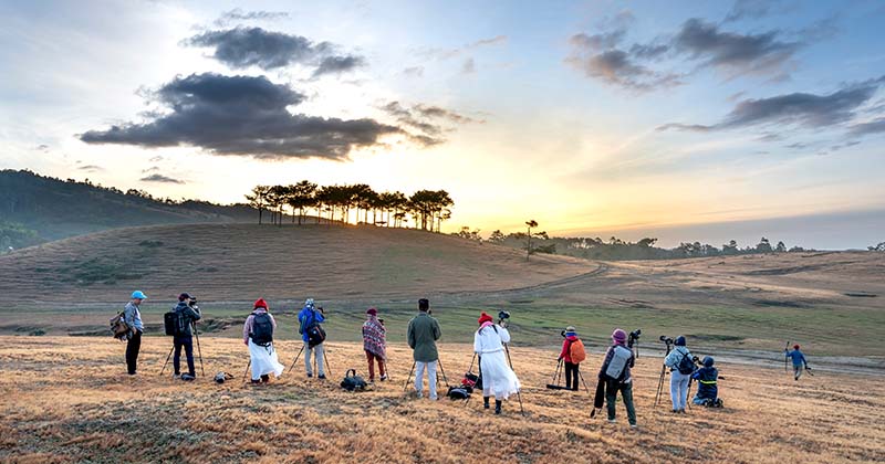 Group of photographers in a line taking photos of the dawn over the hills