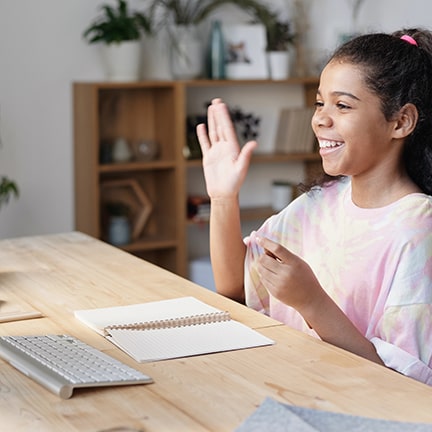 Young lady sitting at a desk and taking part in a virtual class.